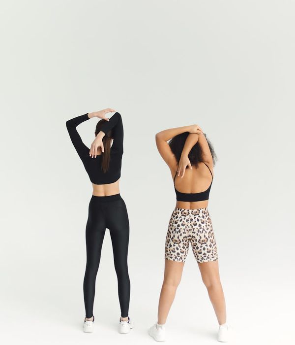Woman performing a dynamic stretching exercise in a dark studio.